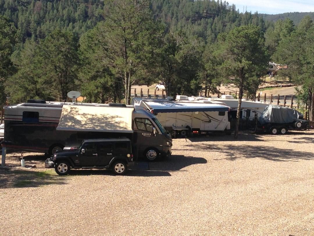 Motorhomes parked on terraced sites with a forested hillside behind